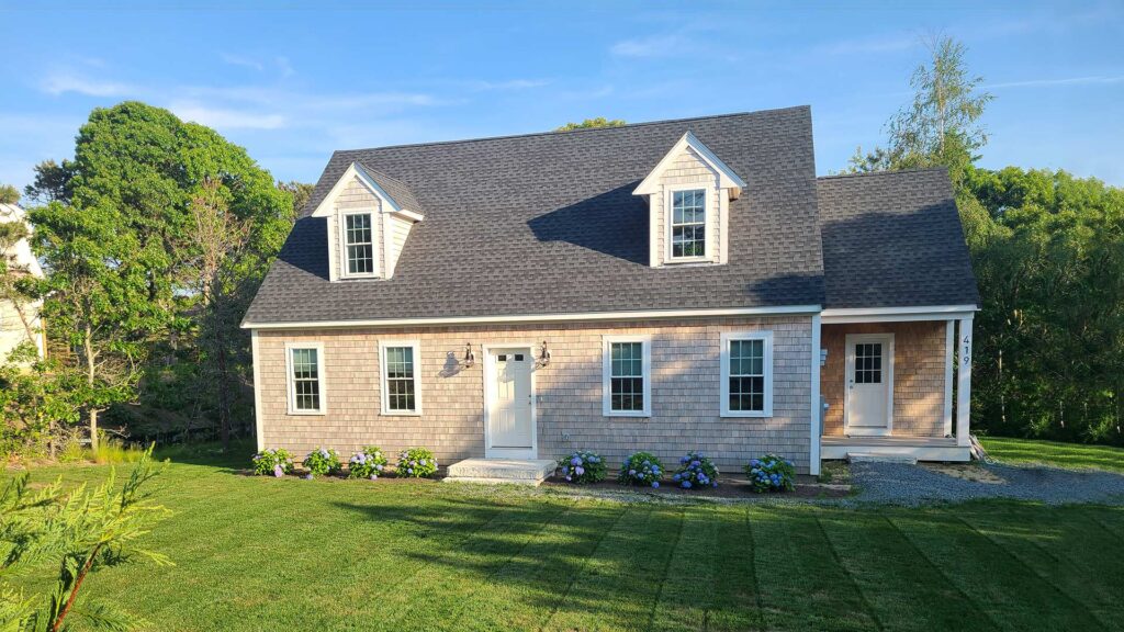 A lovely pink ADU with gray shingles on a well-manicured lawn