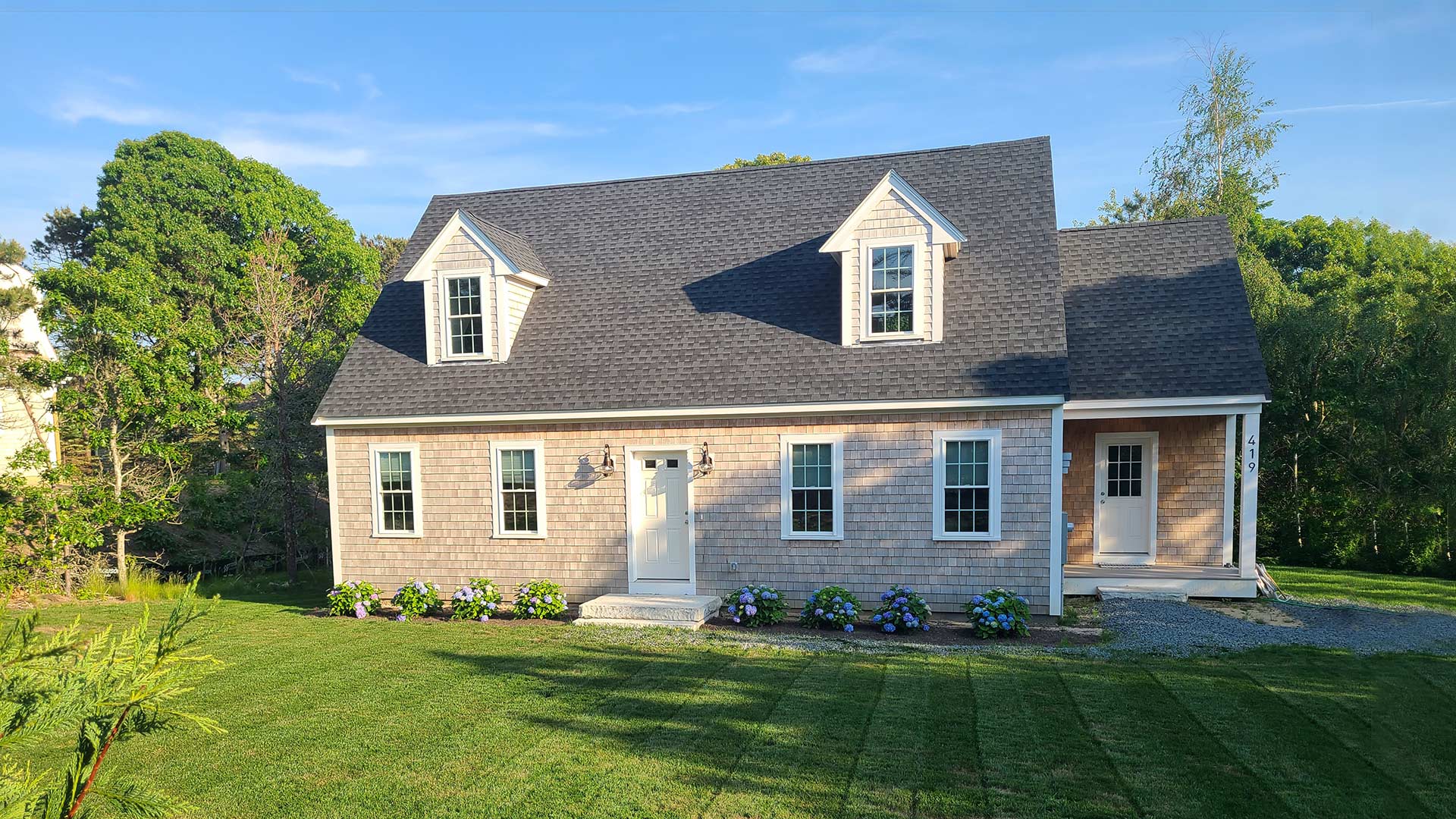 A lovely pink ADU with gray shingles on a well-manicured lawn